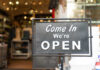 A black sign with white text that says 'Come In We're OPEN'