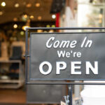 A black sign with white text that says 'Come In We're OPEN'