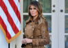 Melania Trump standing outdoors in a brown suede trench coat