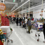 Shoppers queue with carts in a supermarket checkout area