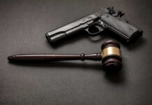 Pistol and judge's gavel on dark surface