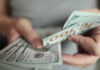 Taxpayer Cash Burned: $9.5B For No Work Hands holding stack of one hundred dollar bills
