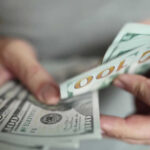 Hands holding stack of one hundred dollar bills