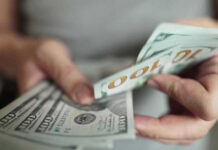 Hands holding stack of one hundred dollar bills