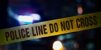 Police tape with blurred emergency lights in the background