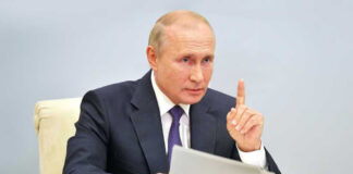 Vladimir Putin, holding papers, in a meeting.