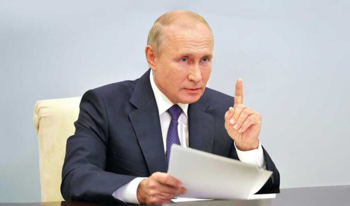 shutterstock_2329478645 Vladimir Putin, holding papers, in a meeting.