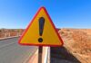 Triangular warning road sign with exclamation mark on a rural highway
