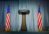 Podium between two American flags on a stage