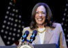 Kamala Harris smiling at a podium with microphones