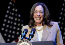 Kamala Harris smiling at a podium with microphones