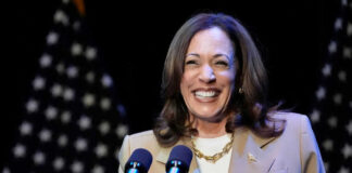 Kamala Harris smiling at a podium with microphones