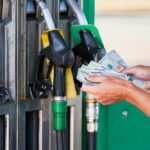 Diesel Hits Shocking Price – Grocery Pain Next Person holding cash at a gas station while preparing to refuel