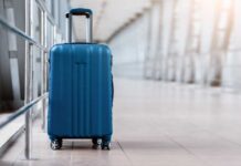 A blue suitcase with wheels positioned in an airport terminal