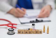 Measles vaccine concept with stethoscope, syringe, and vials on doctor’s desk