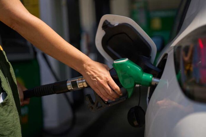 Woman,Refueling,Car,At,Gas,Station,,Holding,Green,Fuel,Pump Person refueling a car at a gas station