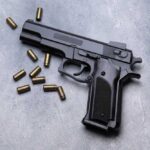 Black semi-automatic pistol with scattered brass cartridges on a gray surface