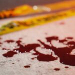 Blood droplets on pavement near yellow caution tape