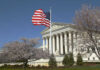Supreme Court Greenlights Crackdown By Trump U.S. Supreme Court building with an American flag and cherry blossom trees