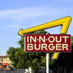 In-N-Out Burger sign with yellow arrow in city setting