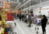 Shoppers queue with carts in a supermarket checkout area