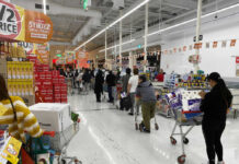 Shoppers queue with carts in a supermarket checkout area
