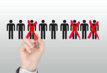 AI Bill Comes Due – Workers Targeted Hand crossing out stick figures with a red marker.