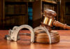 Birthday Trip Turns Deadly – Bartender Charged Wooden gavel and handcuffs on a table.