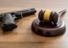 Judge's gavel and handgun on wooden table