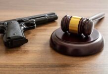 Judge's gavel and handgun on wooden table