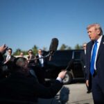 Donald Trump speaks to reporters outdoors near black SUVs