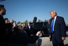 Donald Trump speaks to reporters outdoors near black SUVs