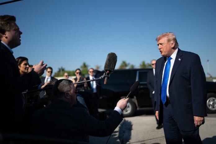 Donald Trump speaks to reporters outdoors near black SUVs